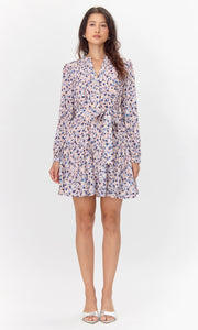 Model wearing a flowy long-sleeve dress with a pink, blue, and purple abstract print.